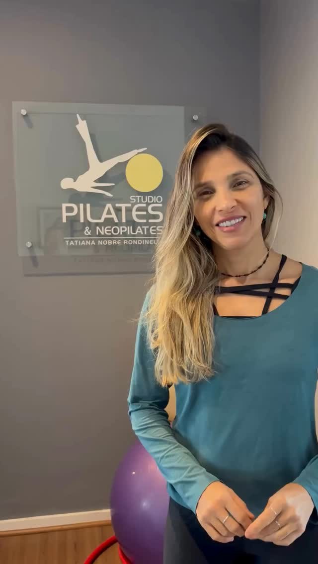 Tatiana Nobre sorrindo em frente à placa do studio